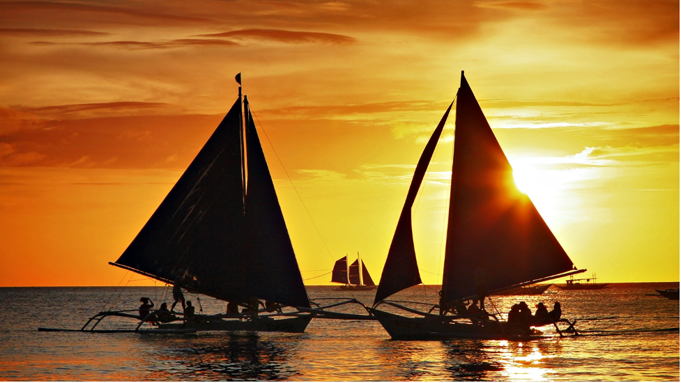 Paraw crossing over sunset